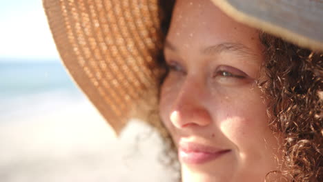 A-young-biracial-woman-wears-a-sunhat-at-the-beach