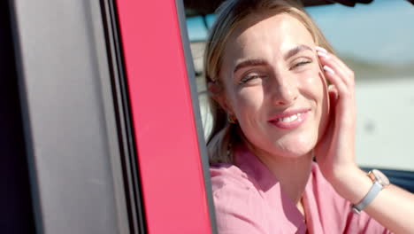 Young-Caucasian-woman-smiles-brightly-in-a-car-on-a-road-trip,-with-copy-space
