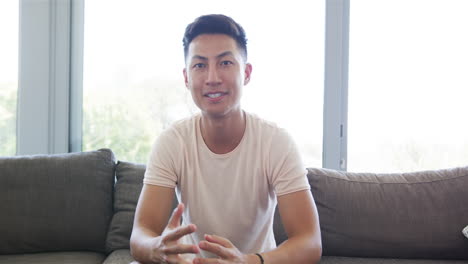 Der-Junge-Asiatische-Mann-Sitzt-Bequem-Zu-Hause-Und-Telefoniert-Mit-Einem-Video