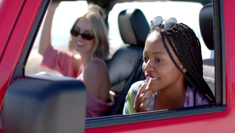 Young-African-American-woman-applies-lipstick-in-a-car-on-a-road-trip
