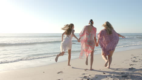 Three-women-enjoy-a-carefree-run-along-the-beach,-with-copy-space
