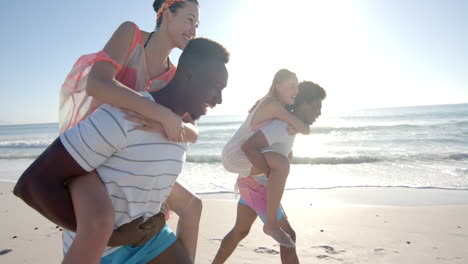 Diverse-couples-enjoy-a-piggyback-race-on-the-beach