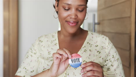Young-biracial-woman-pins-a-'VOTE'-badge-on-her-top
