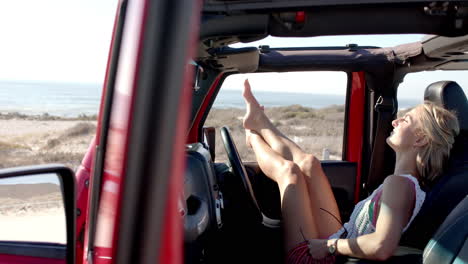 Young-Caucasian-woman-relaxes-in-a-car-on-a-road-trip,-feet-up-on-the-dashboard