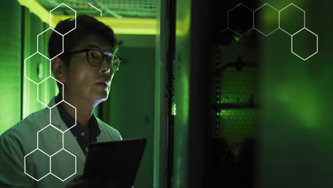 Animation-of-hexagons-over-asian-male-scientist-working-in-server-room