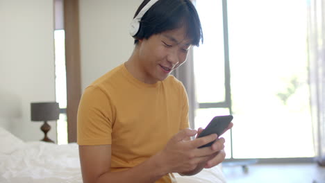 Teenage-Asian-boy-enjoys-music-on-his-phone-at-home