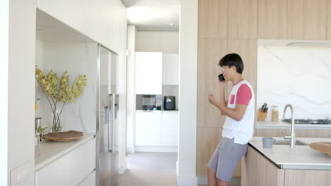 Teenage-Asian-boy-stands-in-a-modern-kitchen,-with-copy-space