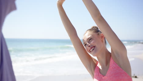 Young-Caucasian-woman-stretches-her-arms-up-on-a-sunny-beach