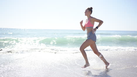 Young-Caucasian-woman-jogs-along-the-shoreline-with-copy-space