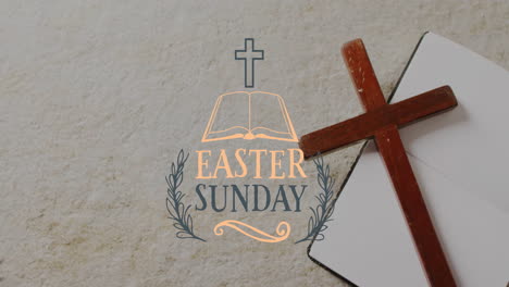 Animation-of-easter-sunday-text-over-christian-cross-and-book-on-grey-background