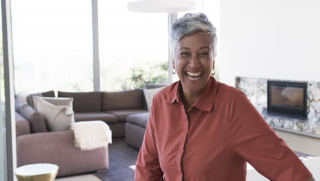 Biracial-woman-with-short-gray-hair,-wearing-a-red-shirt,-smiles-brightly-with-copy-space