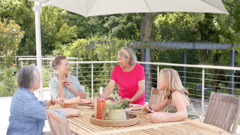 Senior-diverse-group-of-women-enjoy-a-meal-outdoors,-with-copy-space