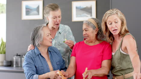 Senior-diverse-group-of-women-preparing-a-meal-together-at-home,-followed-by-a-salad