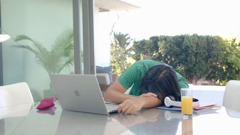 Der-Asiatische-Teenager-Legt-Seinen-Kopf-Während-Des-Studiums-Zu-Hause-Auf-Einen-Schreibtisch