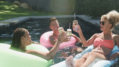 Diverse-friends-enjoy-a-sunny-day-in-the-pool,-with-copy-space