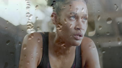 Animation-of-water-droplets-over-tired-african-american-woman-recovering-after-exercise