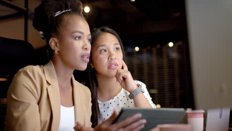 Young-African-American-woman-and-biracial-woman-collaborate-in-a-business-office