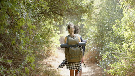 A-young-woman-with-a-backpack-hikes-through-a-lush-forest