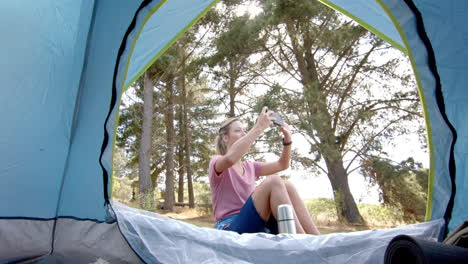 Young-Caucasian-woman-captures-a-moment-with-her-phone-inside-a-tent