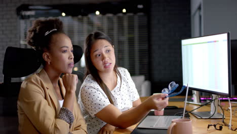 Young-African-American-woman-and-biracial-woman-discuss-business-work-in-an-office