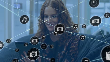 Animation-of-network-of-connections-with-camera-icons-over-caucasian-woman-with-tablet