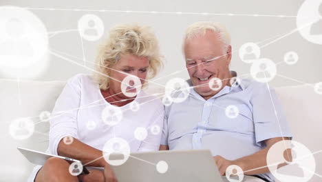 Animation-of-network-of-connections-with-people-icons-over-caucasian-senior-couple-using-laptop