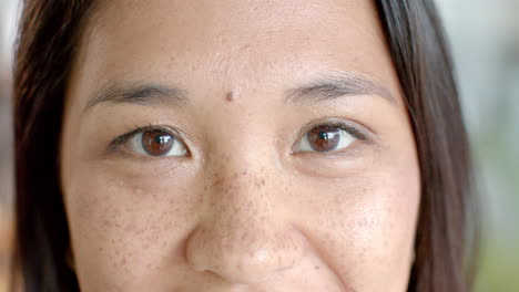 Close-up-of-an-Asian-woman's-face,-highlighting-her-eyes-and-freckles