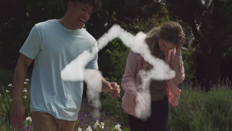 Animation-of-cloud-house-over-happy-diverse-couple-dancing-and-holding-hands-in-garden