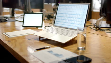 A-modern-business-laptop-open-on-a-spreadsheet-dominates-a-wooden-office-desk