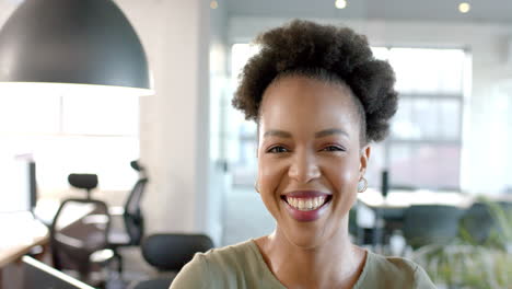 A-young-African-American-woman-smiles-brightly-in-a-business-office-setting