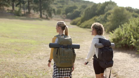 Two-women-with-backpacks-hike-in-a-grassy-outdoor-setting
