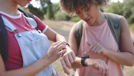 Young-Caucasian-woman-and-biracial-woman-check-their-fitness-trackers-outdoors