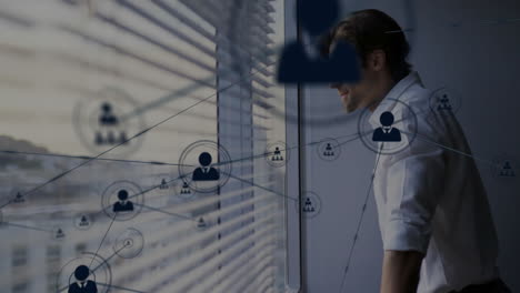 Animation-of-network-of-connections-over-caucasian-man-looking-through-window-in-office