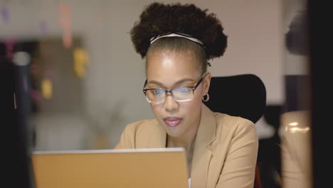 Una-Joven-Afroamericana-Enfocada-Trabaja-Diligentemente-En-Su-Computadora-Portátil-De-Negocios-En-Un-Ambiente-De-Oficina