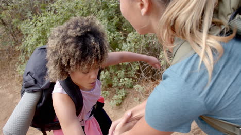 A-young-child-with-curly-hair-receives-help-from-a-woman-outdoors