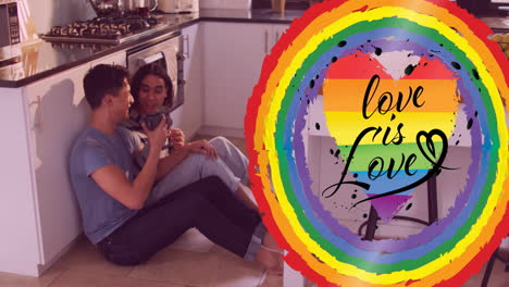 Animation-of-love-is-love-text-and-rainbow-heart-over-diverse-gay-male-couple-talking-in-kitchen