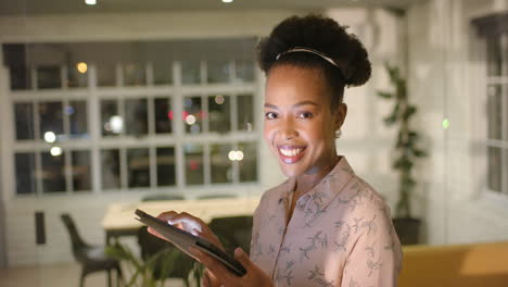 Young-African-American-businesswoman-smiles-holding-a-tablet-in-an-office-with-copy-space