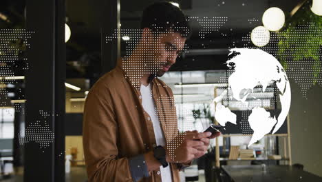 Animation-of-globe-and-world-map-over-biracial-businessman-using-smartphone-in-office