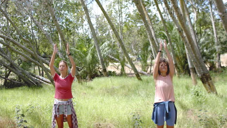 Young-Caucasian-woman-and-young-biracial-woman-practice-yoga-outdoors