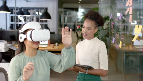 Young-African-American-woman-guides-a-biracial-woman-in-a-business-VR-experience