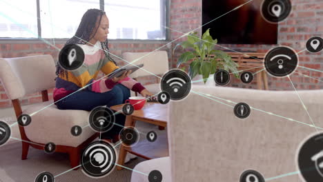 Animation-of-network-of-connections-with-wifi-icons-over-african-american-woman-using-tablet