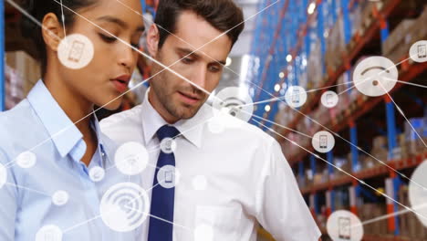 Animation-of-network-of-connections-with-icons-over-diverse-workers-talking-in-warehouse
