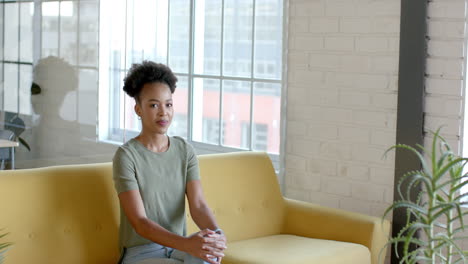 Eine-Junge-Afroamerikanische-Frau-Sitzt-Auf-Einem-Gelben-Sofa-In-Einem-Geschäftsbüro-Mit-Platz-Zum-Kopieren