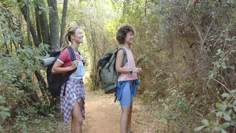 Two-women-with-backpacks-hike-on-a-forest-trail