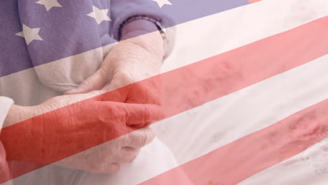 Animation-of-flag-of-usa-over-senior-caucasian-female-patient-holding-hands