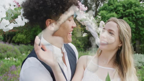 Animation-of-cloud-house-over-happy-diverse-couple-smiling-in-garden-on-wedding-day
