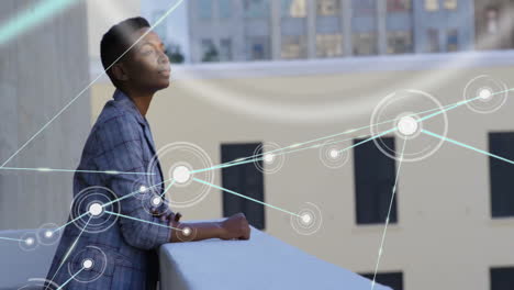 Animation-of-network-of-connections-over-african-american-businesswoman-standing-on-balcony