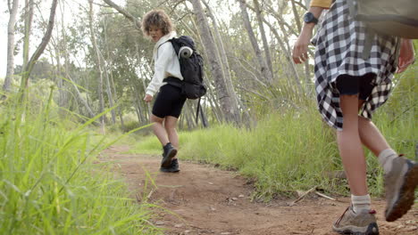 Child-with-curly-hair-is-walking-on-a-dirt-path,-smiling-towards-the-camera