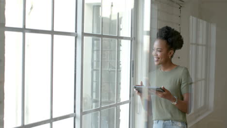 Young-African-American-woman-stands-by-a-window,-with-copy-space