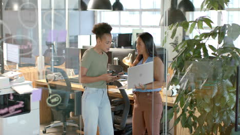 Young-African-American-woman-discusses-with-biracial-woman-in-a-modern-office